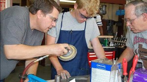 Jacobs Engineering's Steve Rogers and Clear Creek HS teacher Bill Gibbs help Josh Hartnett learn the intricacies of making sheet metal flight ready for space.